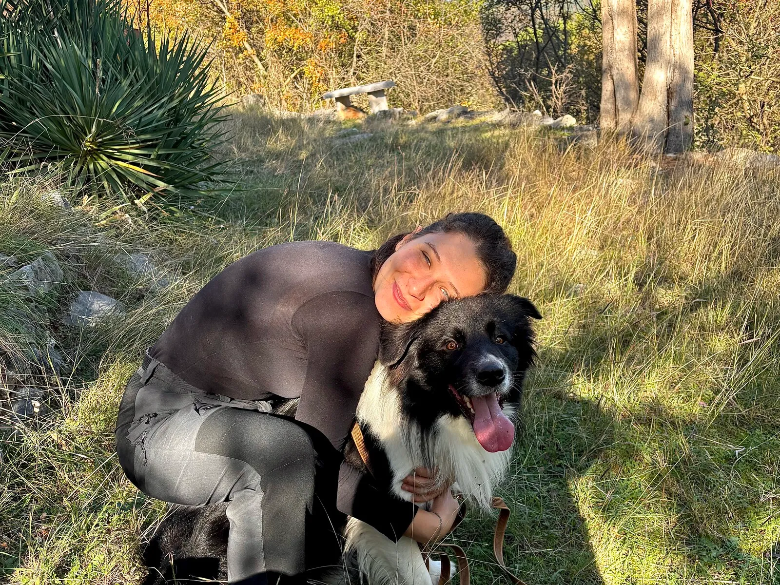 Io accoccolata vicino a un cane in un prato, durante una giornata trascorsa insieme